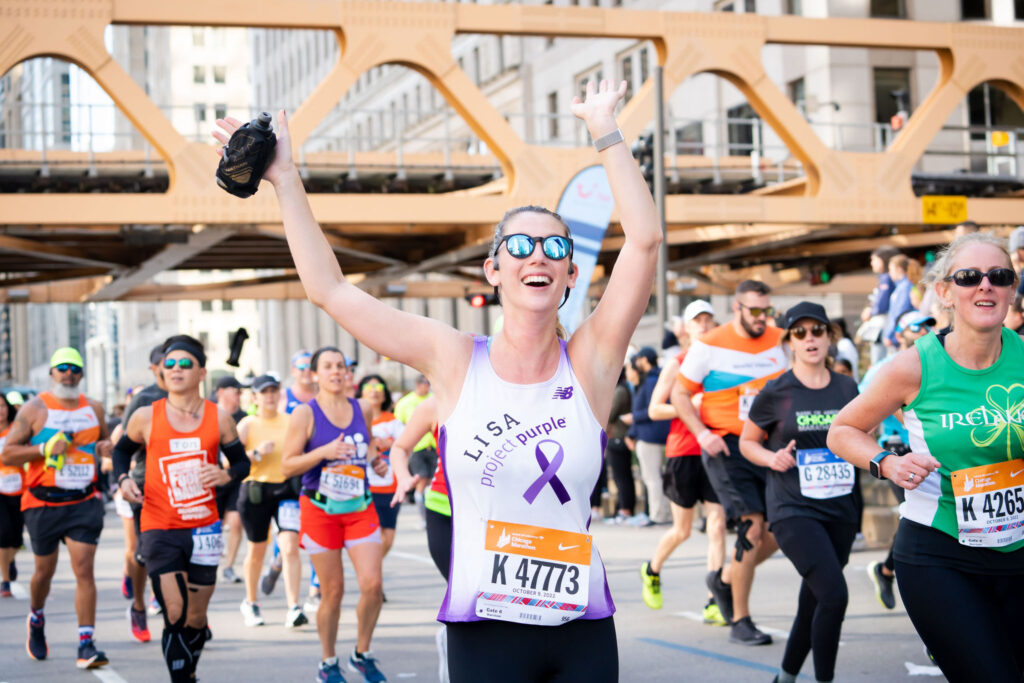 Chicago marathon runner with arms up in Project Purple singlet